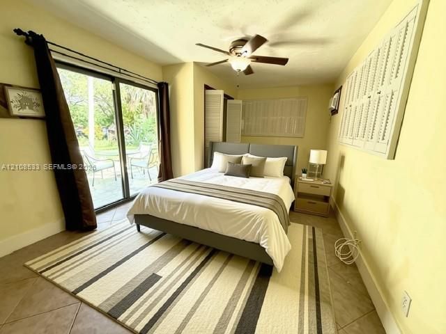Sliding glass door, tiled flooring, ceiling fan with integrated lighting, and louvered wall shutters