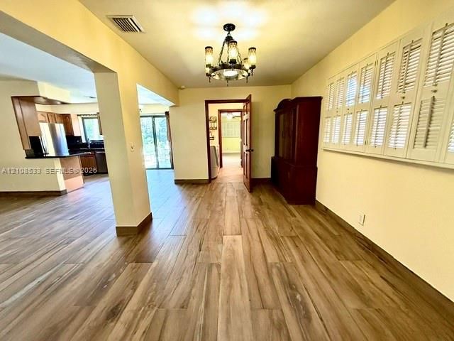 Interior space featuring wood-finish flooring, a multi-arm candelabra chandelier, and plantation shutters