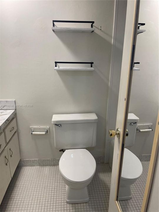 Vanity with a solid-surface countertop, dual wall-mounted floating shelves with metal accents, and mosaic tile flooring