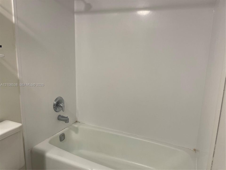 Bathtub and shower combination featuring a polished chrome single-handle mixing valve and matching tub spout
