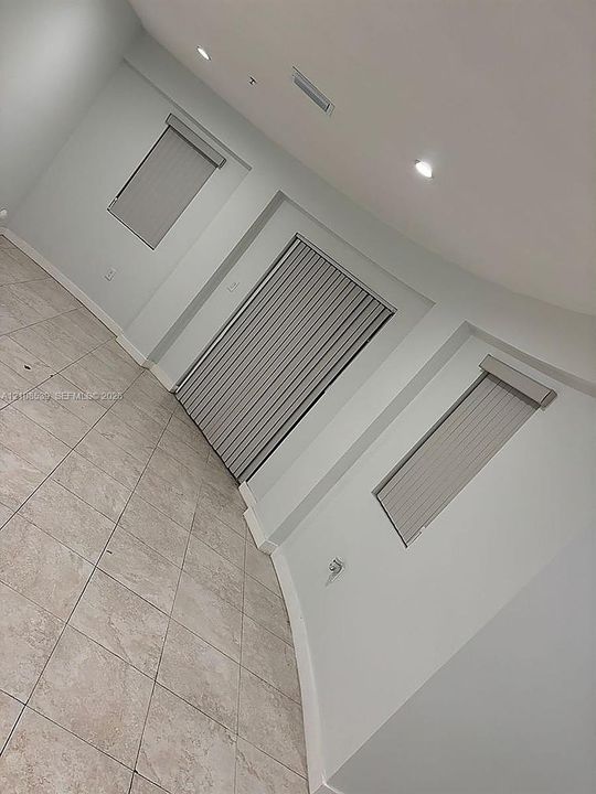 Neutral-toned tile flooring, recessed ceiling lighting, and vertical window blinds