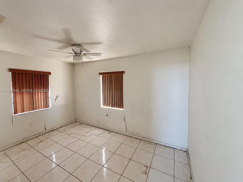 Room featuring ceramic tile flooring, vertical window blinds, and a ceiling fan with an integrated light fixture