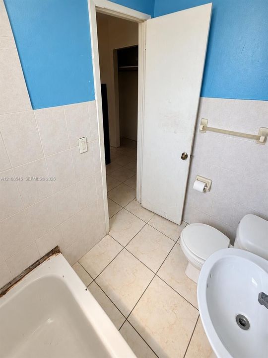 Bathroom featuring light-toned tile flooring, white porcelain fixtures, and wall tiling