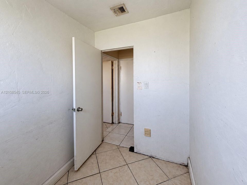 Neutral interior space featuring ceramic tile flooring, solid core doors, and smooth-finish walls