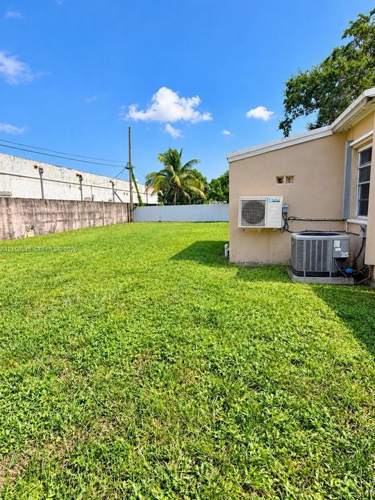 Expansive rear lawn with concrete masonry perimeter wall and exterior climate control units