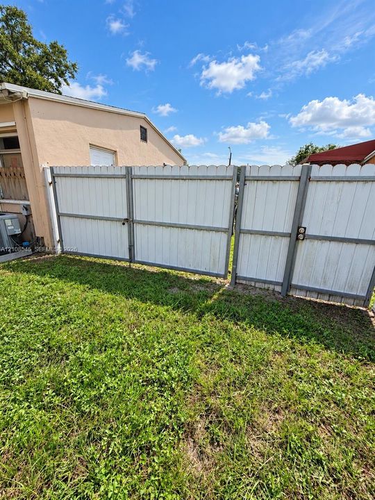Exterior space featuring a white scalloped-top fence with metal framing and a lawn area