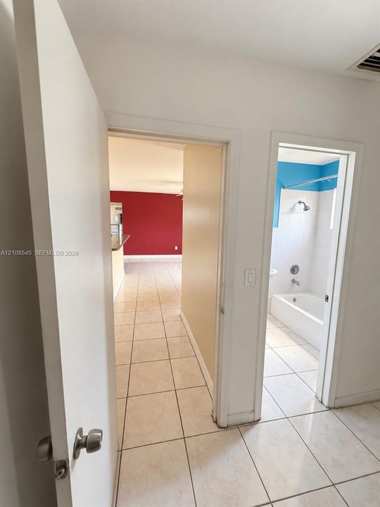 Ceramic tile flooring, white-tiled shower-tub combination, and chrome hardware fixtures