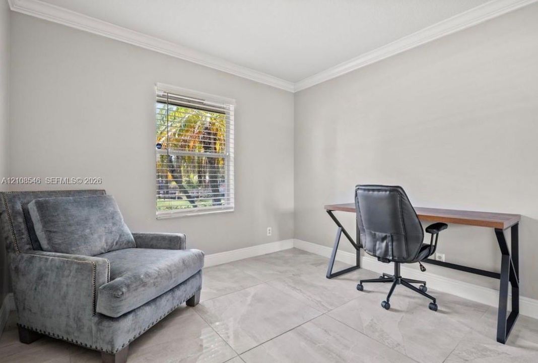 Neutral-toned walls with crown molding, large-format tile flooring, and window featuring horizontal blinds