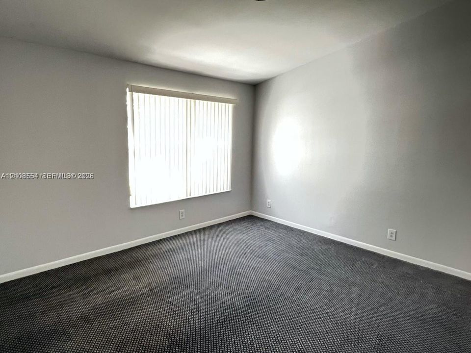 Neutral wall tones, gray carpeting, and vertical window blinds
