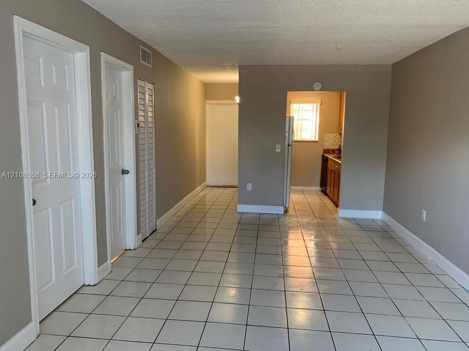 Neutral-toned interior featuring ceramic tile flooring, solid-core interior doors, louvered closet doors, and recessed kitchen cabinetry