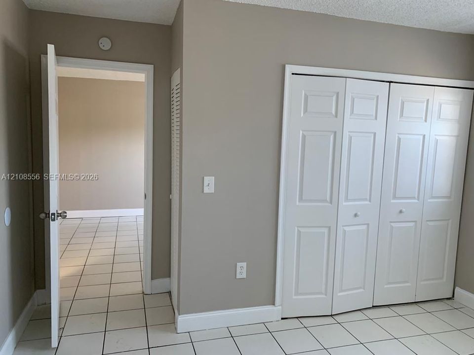 Neutral-tone walls, white ceramic tile flooring, and a multi-panel white closet door