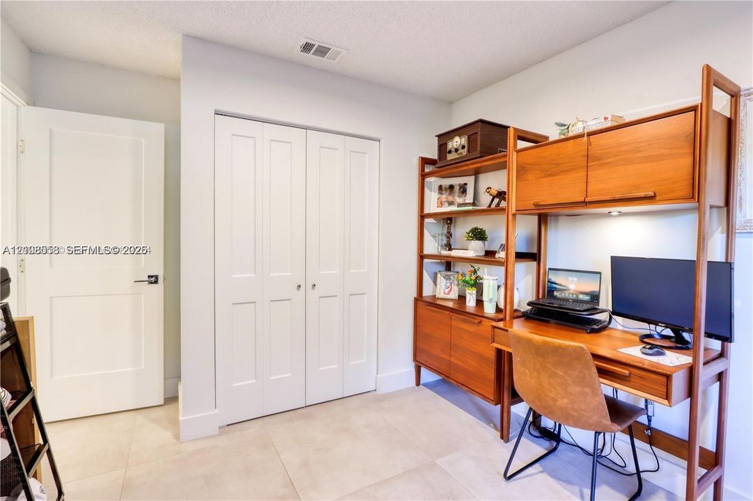 Neutral-toned tile flooring, white interior doors, and double-panel closet doors with hardware