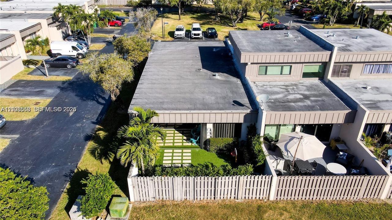 Multi-unit residential structure with flat roofing and a private, fenced-in patio area featuring paver-and-turf hardscaping