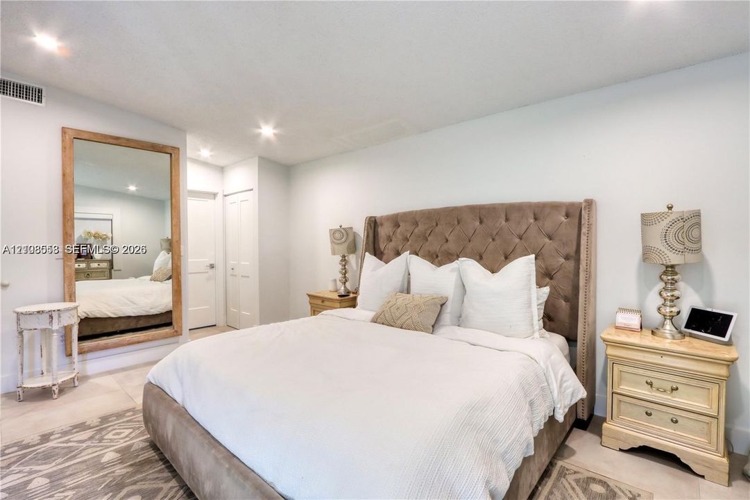 Large wall-mounted mirror with a wood-finish frame and neutral flooring throughout