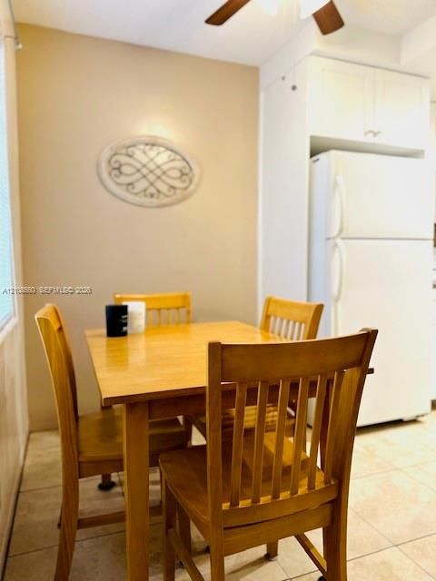Neutral-toned kitchen featuring ceramic tile flooring, ceiling-mounted paddle fan, and white cabinetry
