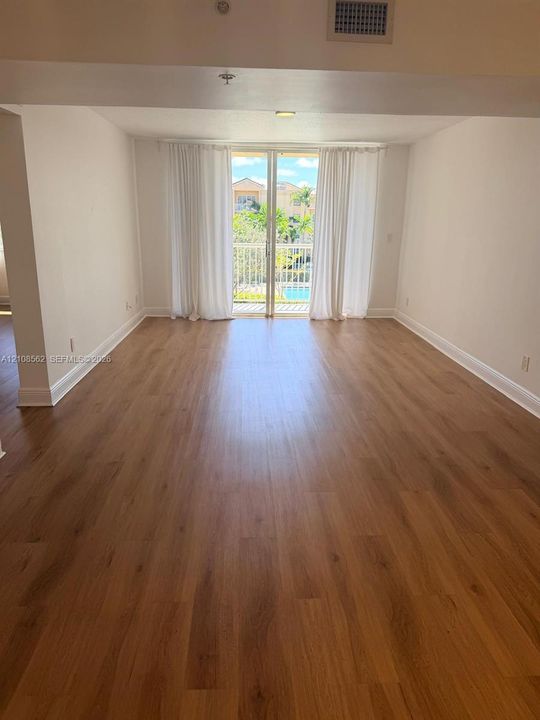 Living area featuring wood-finish flooring and glass sliding doors opening to a private balcony