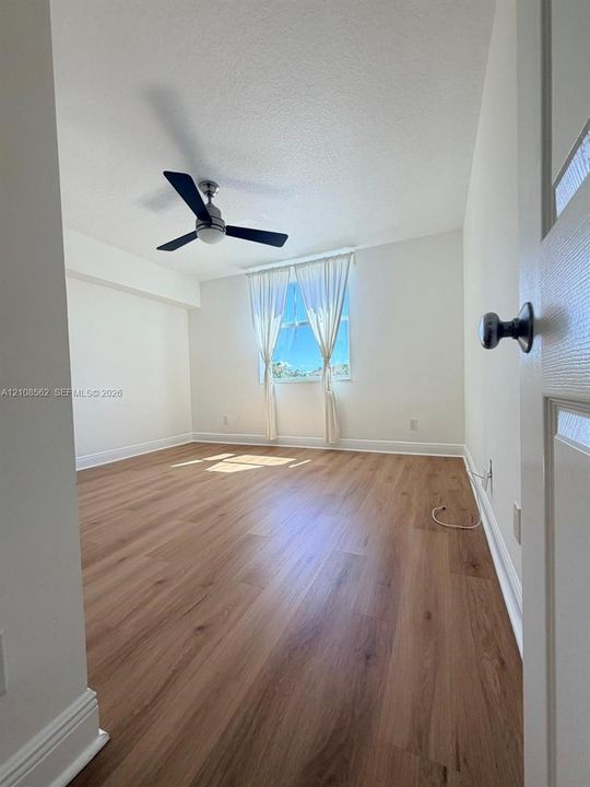 Interior space featuring wood-finish flooring, neutral wall paint, and a modern ceiling fan