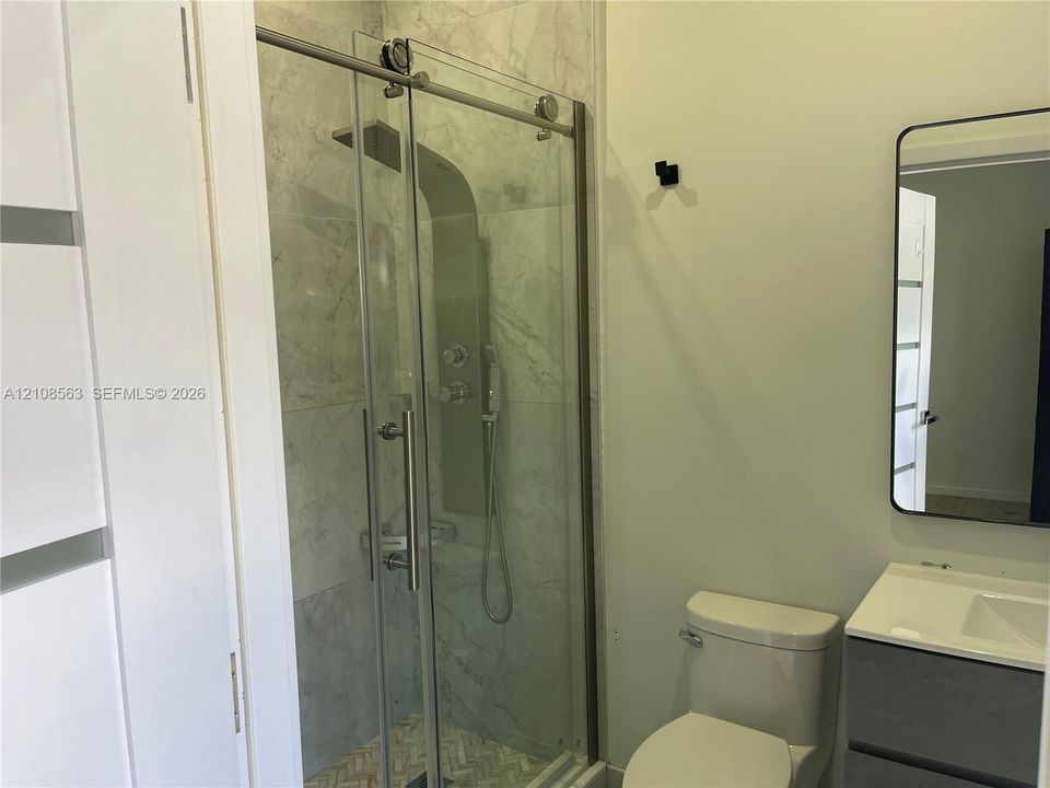 Shower enclosure featuring a stainless steel shower panel system, sliding glass doors, and tiled walls