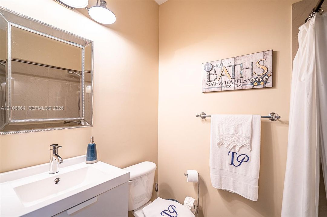 Bathroom featuring a white vanity with integrated basin, polished chrome faucet, rectangular wall-mounted mirror, and overhead light fixture