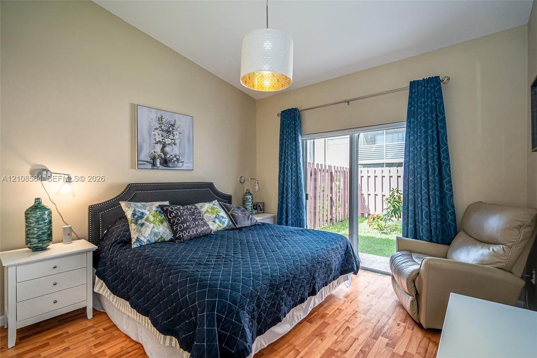 Room featuring wood-finish flooring, sliding glass doors, a drum pendant light fixture, and two wall-mounted articulating reading lamps