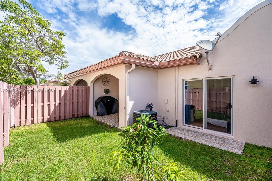Private backyard featuring a covered patio, paved stone hardscaping, and privacy fencing