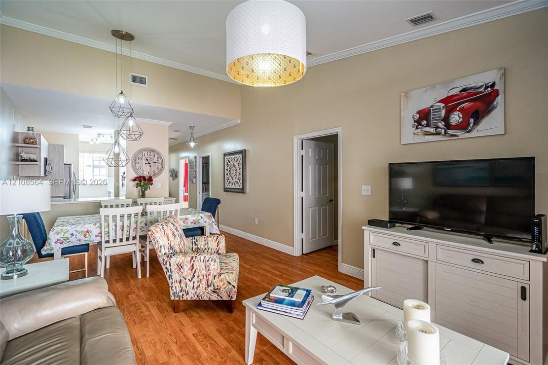 Vaulted ceilings, wood-finish flooring, recessed lighting, and a large-format drum pendant light fixture
