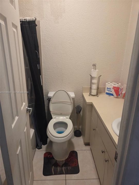 Bathroom featuring ceramic tile flooring, built-in cabinetry with a solid surface countertop, and a white porcelain sink and toilet