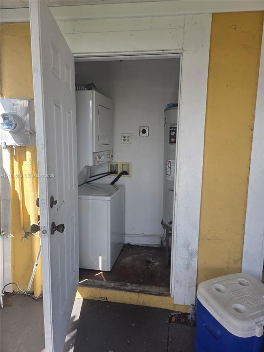 Utility area featuring a stacked laundry unit and a dedicated water heater