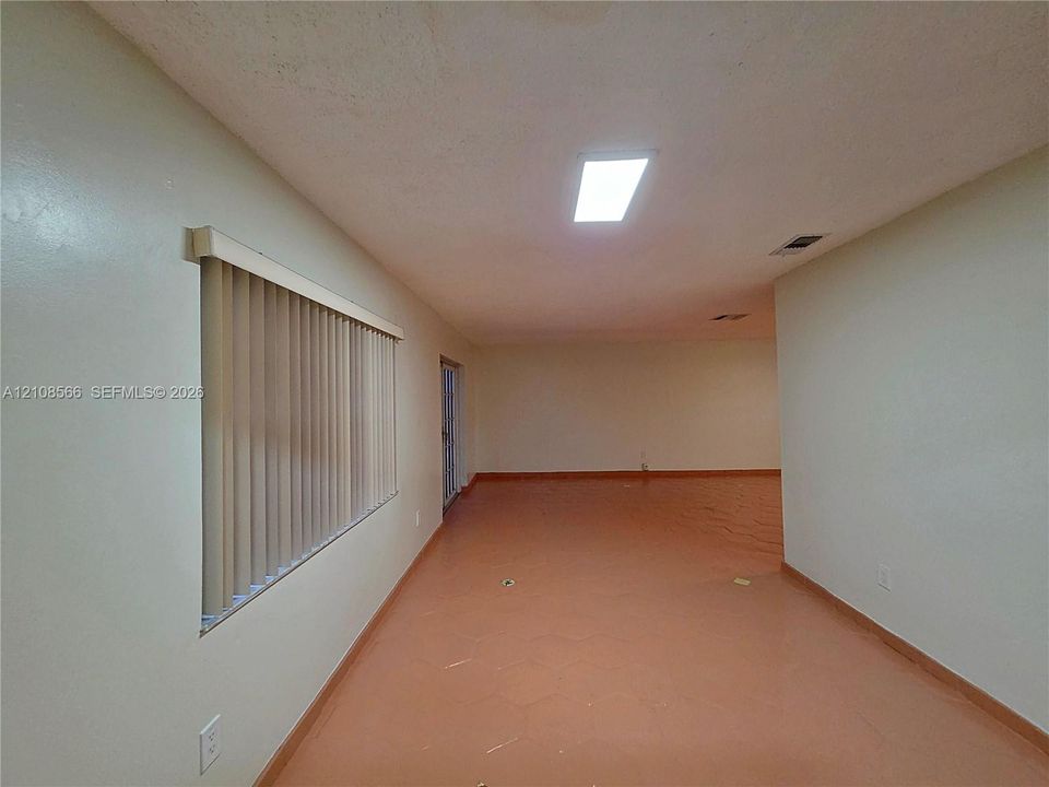 Neutral interior space featuring hexagonal tile flooring, vertical window blinds, and a recessed ceiling light fixture