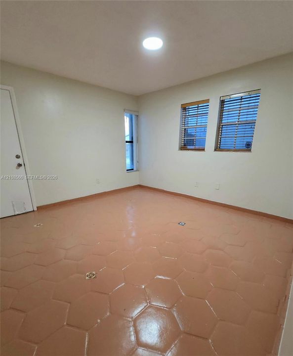 Interior room featuring hexagonal tile flooring, three multi-pane windows with horizontal blinds, and a circular recessed ceiling light