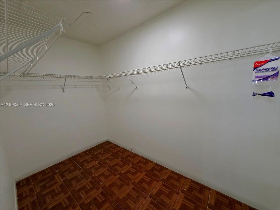 Storage space featuring white walls and wire shelving systems installed with wood-finish flooring