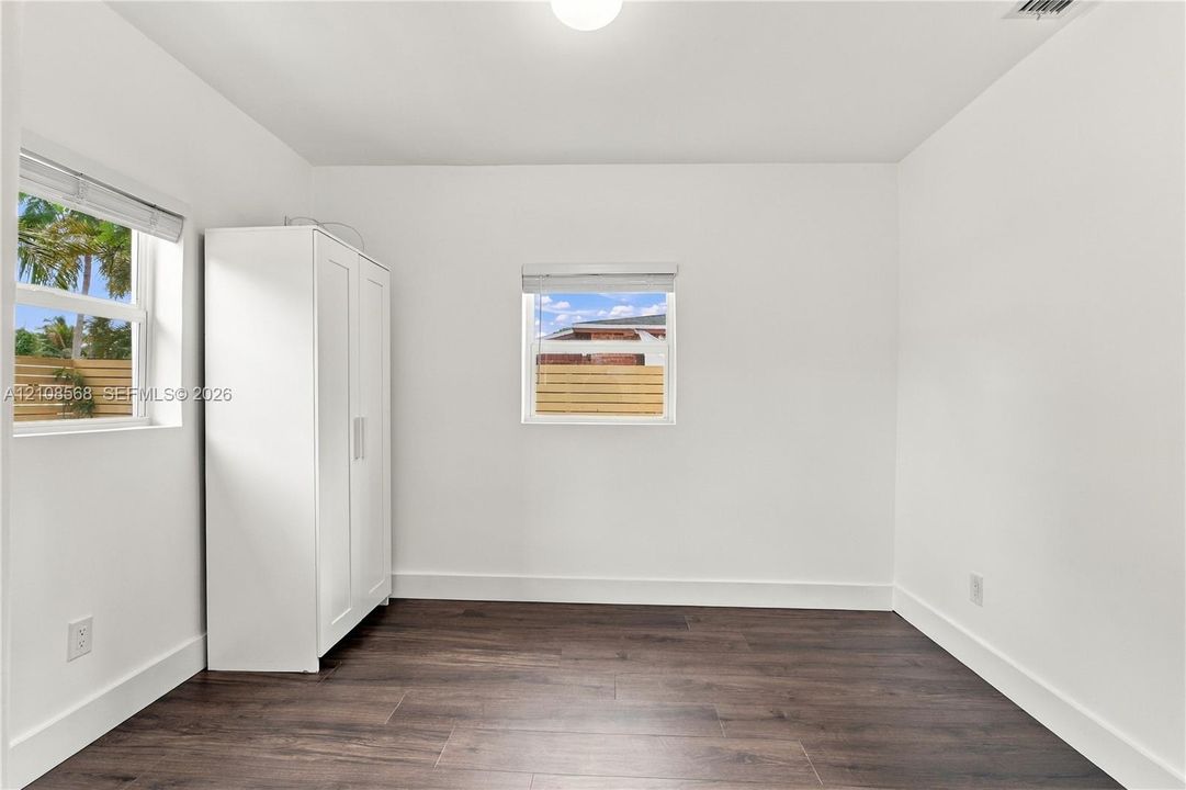 Interior room featuring wood-finish flooring, white walls, and dual windows with horizontal blinds