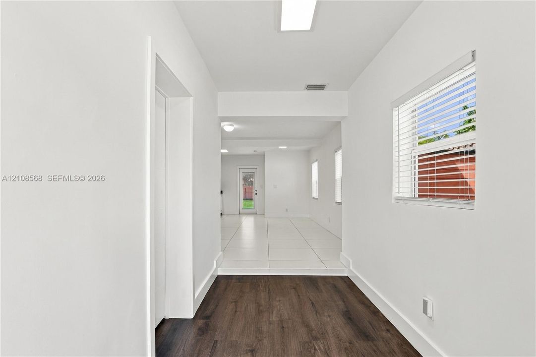 Interior space featuring wood-finish flooring, white walls, recessed ceiling lighting, and horizontal window blinds