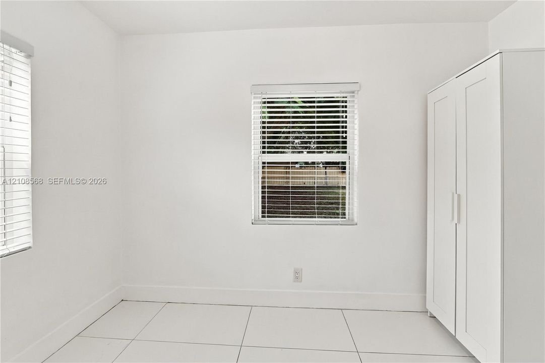 Interior space featuring neutral wall tones, large-format tile flooring, and windows fitted with horizontal blinds