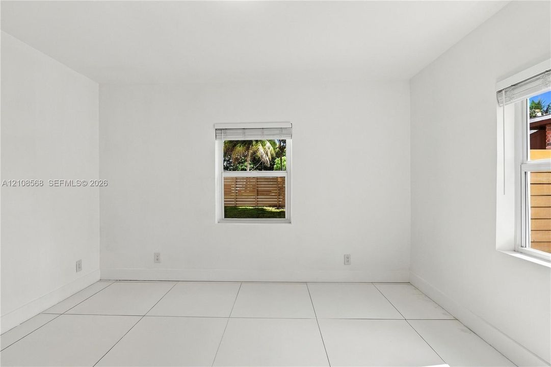 Neutral-toned interior featuring large-format tile flooring and multiple windows with horizontal blinds