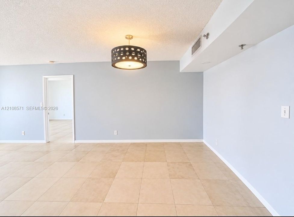 Neutral-toned tile flooring, light-colored walls, and a decorative drum-style ceiling light fixture