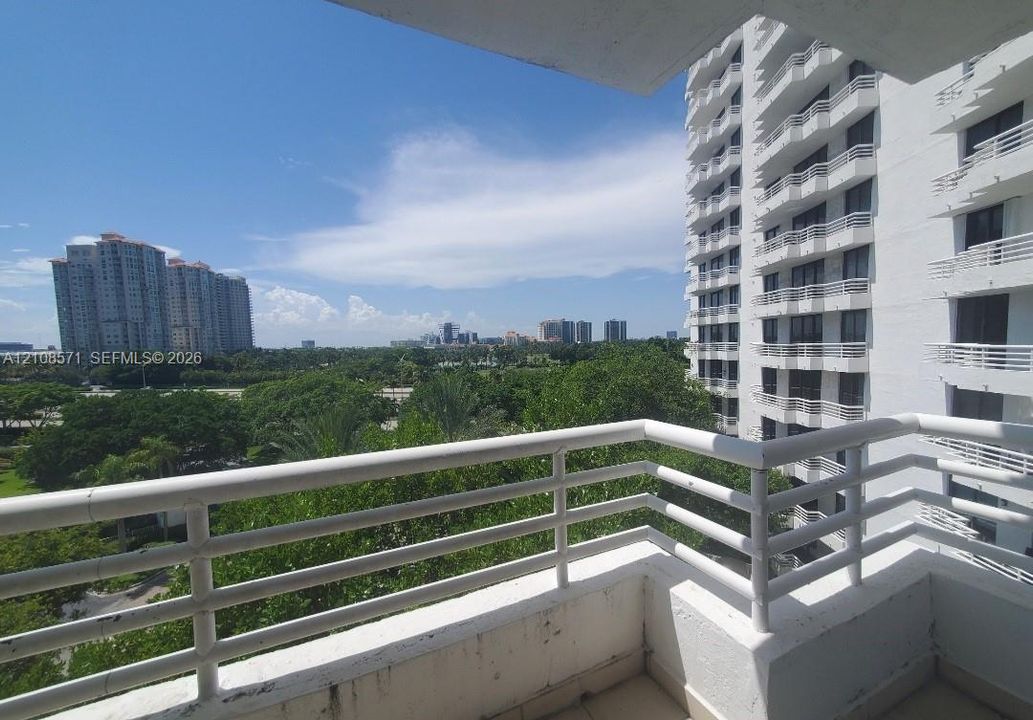 Covered balcony featuring white railings, concrete flooring, and an expansive exterior landscape