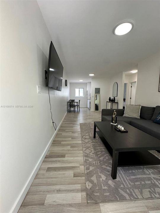 Neutral-toned wood-finish flooring, recessed lighting, and wall-mounted television bracket