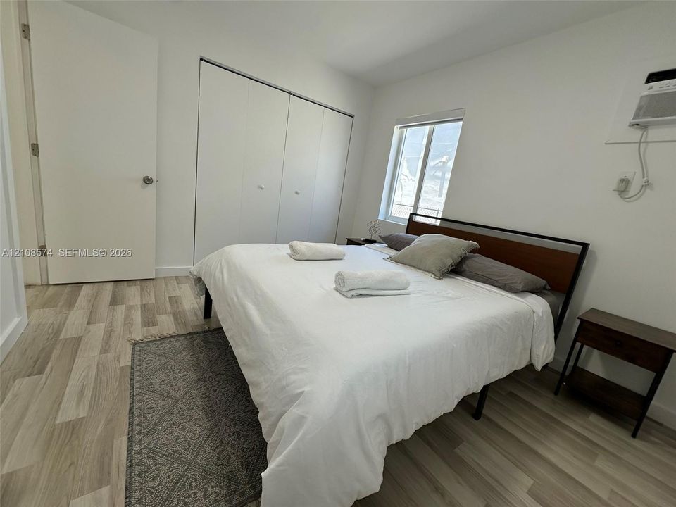 Bedroom featuring wood-finish flooring, white walls, double-door closet, and single window
