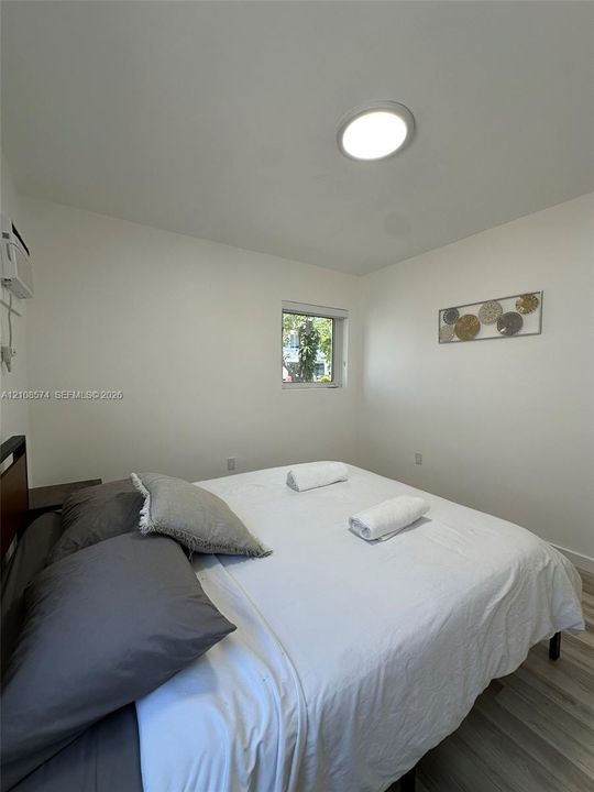 Room featuring wood-finish flooring, a flush-mount circular ceiling light, and a window