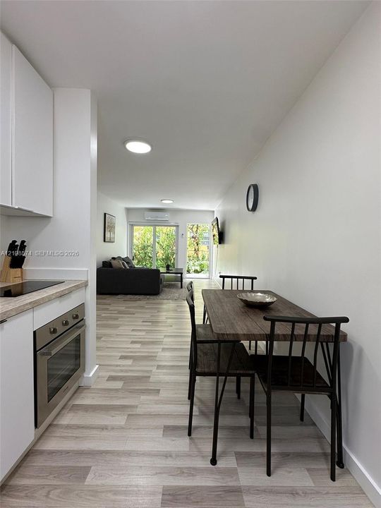 Kitchen featuring white flat-panel cabinetry, light-toned countertop, and stainless steel wall-mount oven