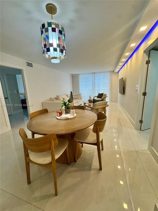 Polished tile flooring, recessed ceiling lighting, decorative multi-colored glass pendant fixture, and recessed cove lighting with blue accent