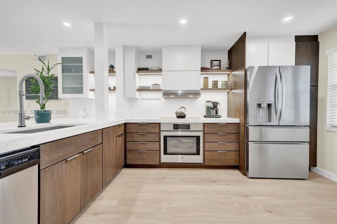 Kitchen featuring wood-finish cabinetry, white countertops, recessed lighting, stainless steel appliances, and integrated open shelving