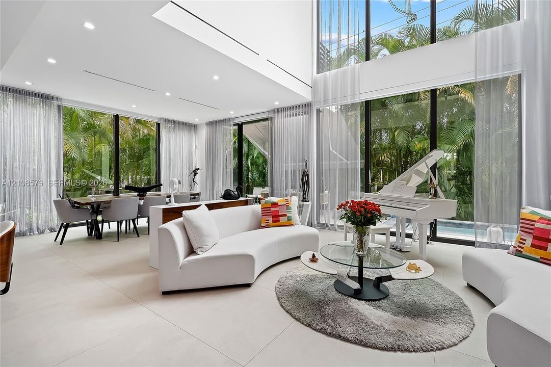 Double-height ceilings, floor-to-ceiling glass walls, large-format tile flooring, and recessed lighting