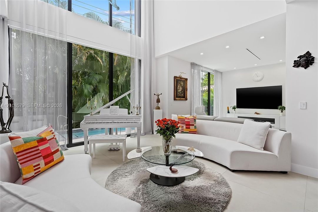 Double-height ceilings, floor-to-ceiling glass wall, recessed lighting, and large-format tile flooring