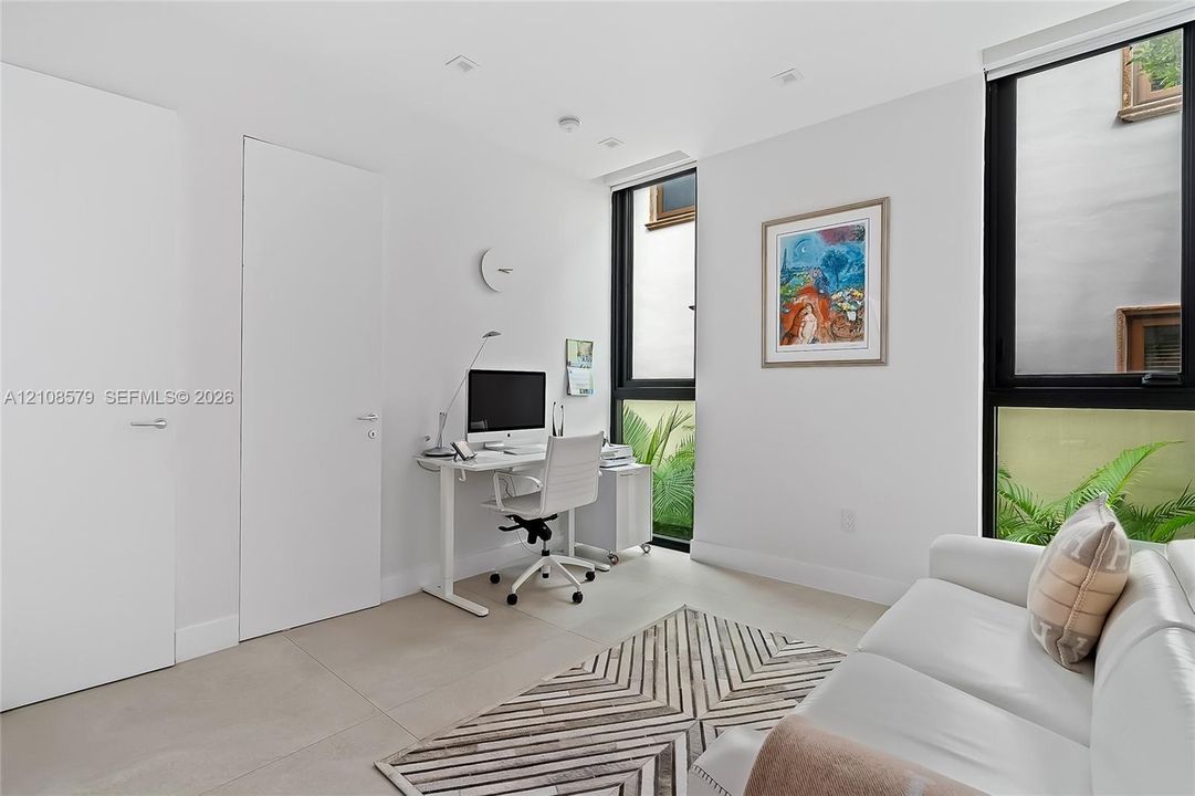 Neutral-toned floor tiles, floor-to-ceiling windows with black frames, and recessed ceiling lighting