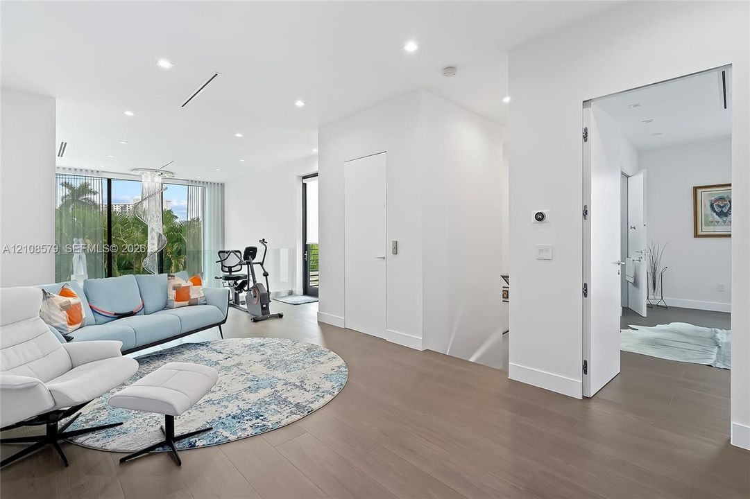 Interior space featuring wood-finish flooring, floor-to-ceiling glass windows, recessed ceiling lighting, and crisp white wall finishes