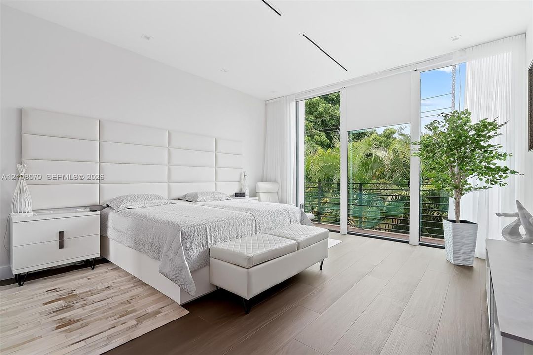 Floor-to-ceiling windows, wood-finish flooring, recessed lighting, and wall-mounted grid headboard paneling