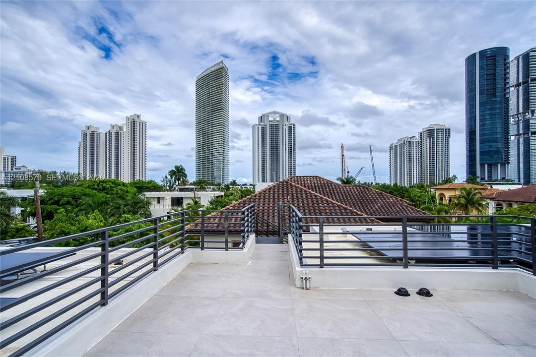 Rooftop terrace featuring large-format tile flooring and horizontal metal railings