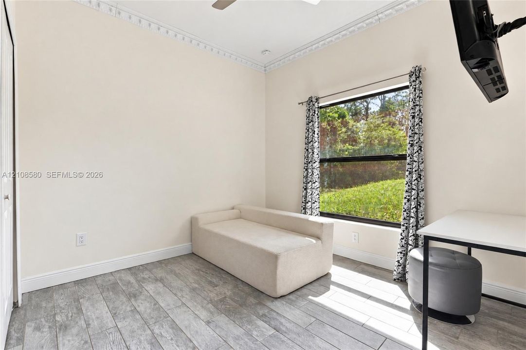 Room featuring wood-finish tile flooring, decorative crown molding, and a large window